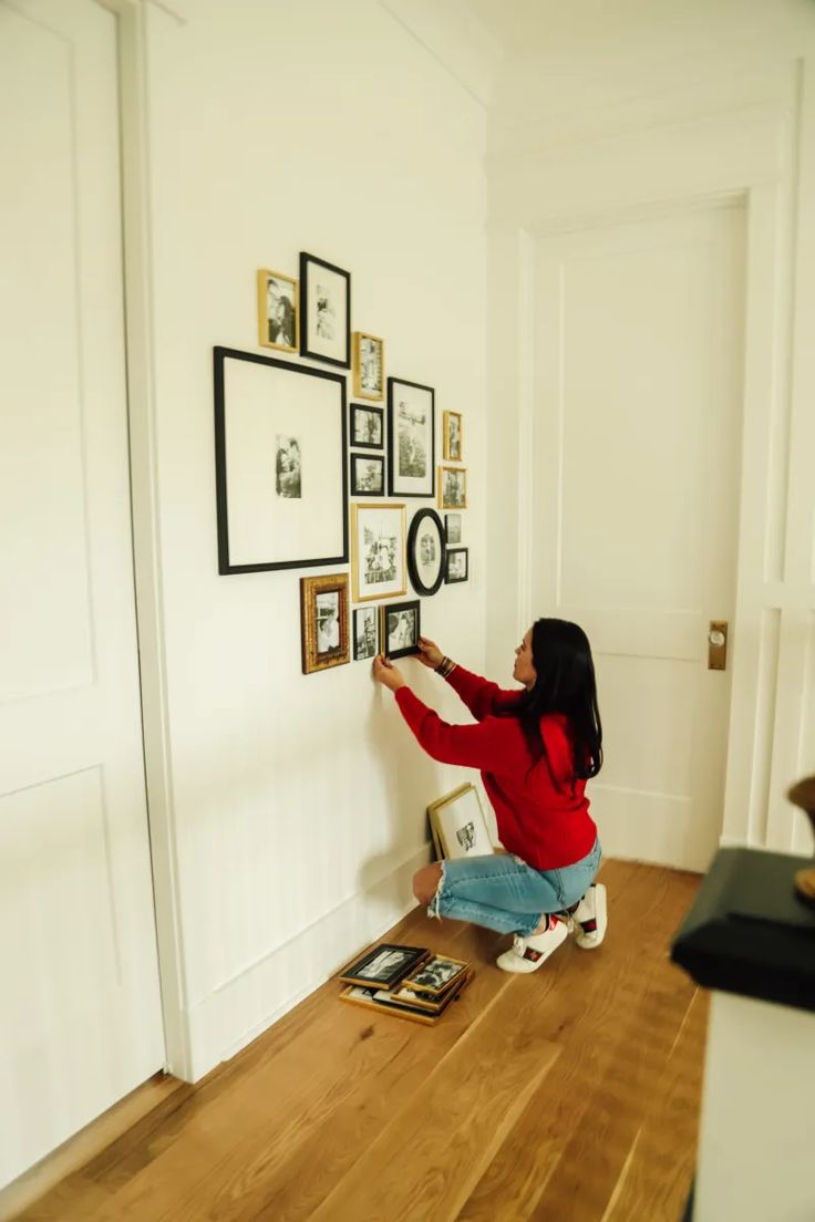 a woman sitting on the floor in front of a wall with pictures