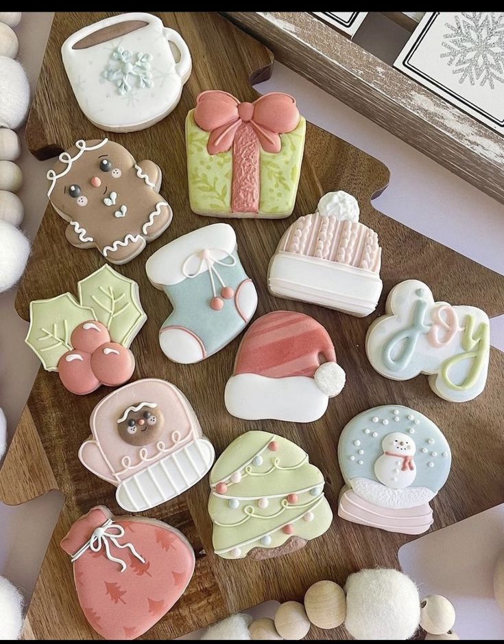 decorated cookies are on a wooden board next to white balls and other holiday decorating items