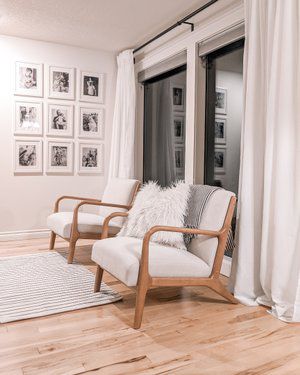 a living room with two chairs and pictures on the wall