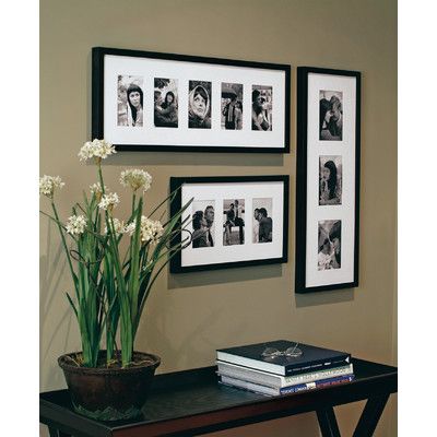 a table with some flowers and pictures on the wall above it, along with books