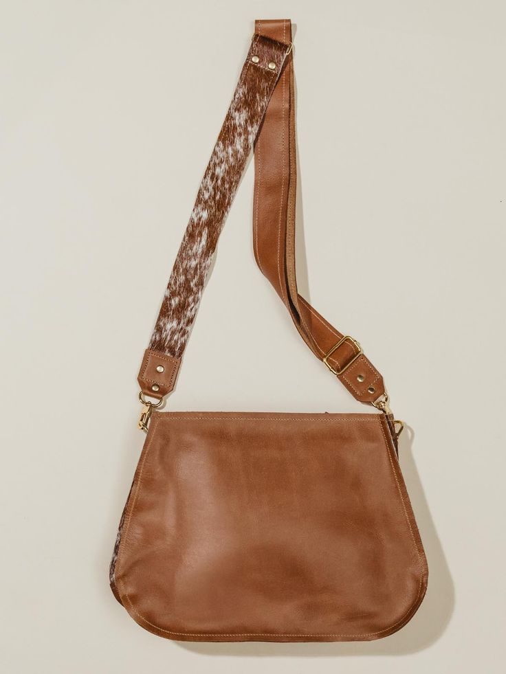 This brown leather messenger bag is the ideal crossbody companion for everyday use, providing comfort and elegance in one stylish package. Meticulously handmade and crafted for both style and functionality, it boasts a combination of premium materials, featuring sumptuous Cognac leather and genuine brown and white cowhide. And it offers practicality with its well-designed interior and exterior pockets, making it easy to organize your essentials. The zipper closure features a sleek leather pull a Brown Leather Messenger Bag, Cowhide Bag, Leather Messenger Bag, Bag Handmade, Leather Messenger, Leather Pulls, Cowhide Leather, Cognac, Interior And Exterior