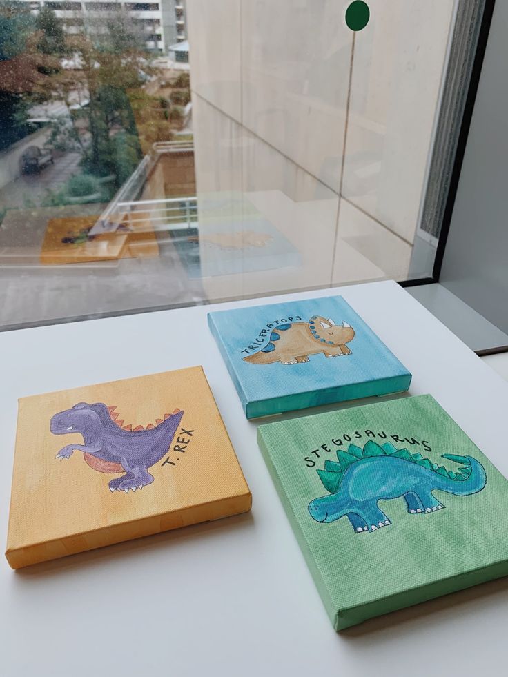 three children's books sitting on top of a white table next to a window