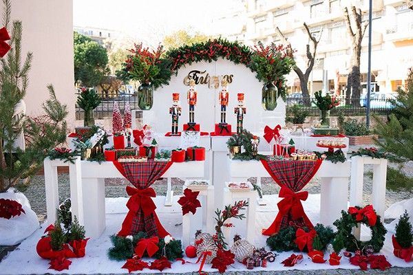 christmas decorations on display in front of a white bench with red bows and presents around it