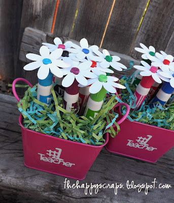 three red buckets filled with flowers sitting on top of a wooden bench