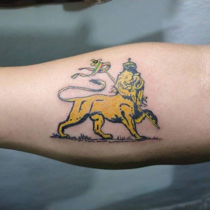 a tattoo on the arm of a man with a lion and flag in his hand