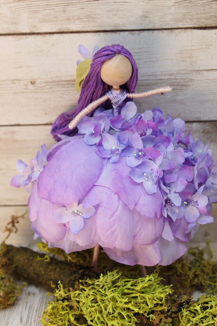 a doll sitting on top of a purple flower