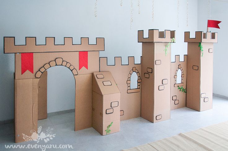 cardboard castles are lined up on the floor in front of a wall with a red flag