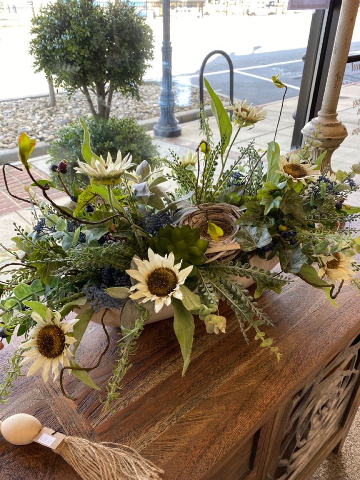 a vase filled with flowers sitting on top of a wooden table next to a window