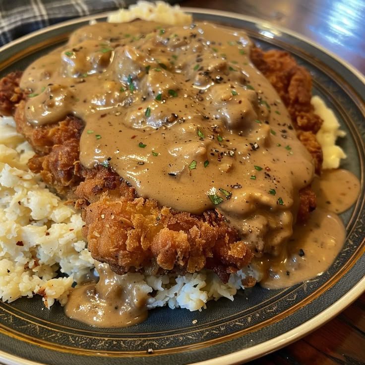 a plate topped with meat and gravy covered in gravy on top of mashed potatoes