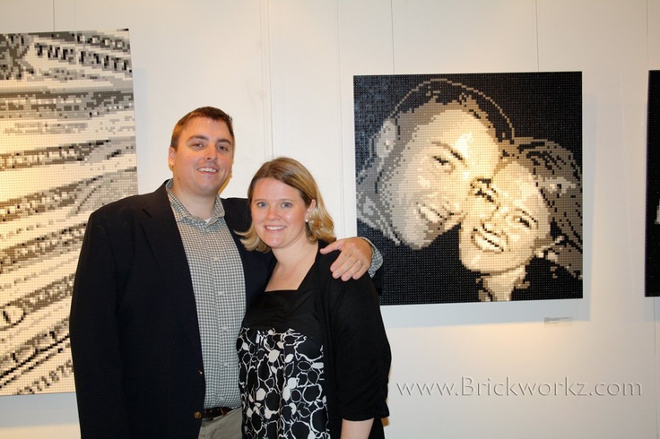 two people standing next to each other in front of some art work on the wall