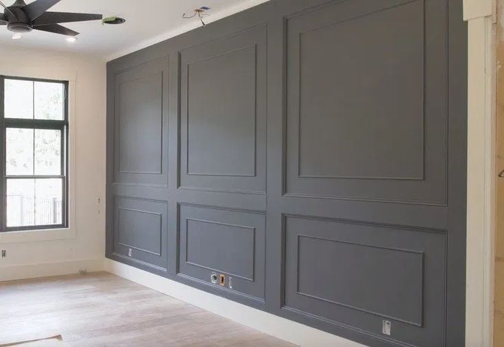 an empty room with gray walls and ceiling fan