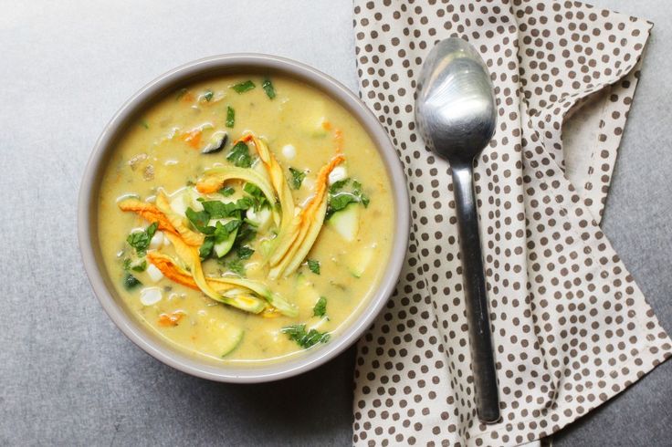 a white bowl filled with soup on top of a table next to a silver spoon