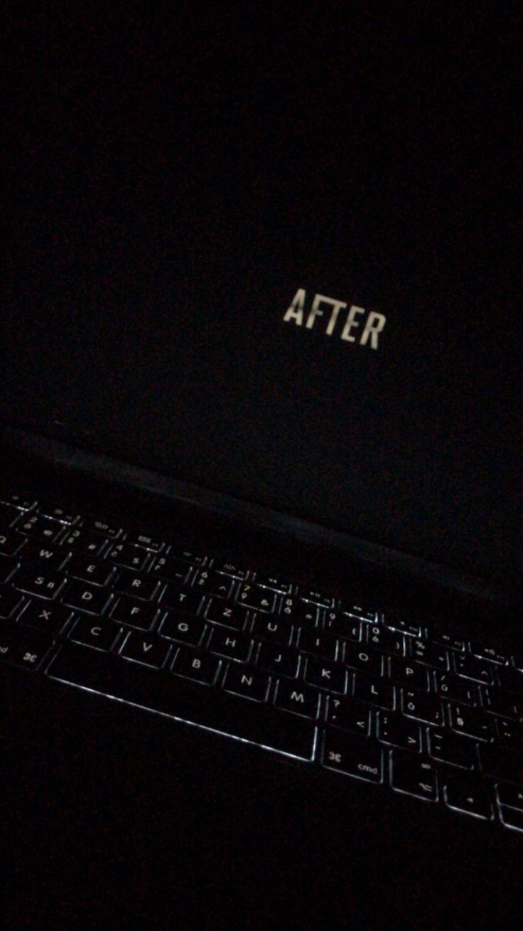 an open laptop computer sitting on top of a black keyboard in the dark with the word after written on it