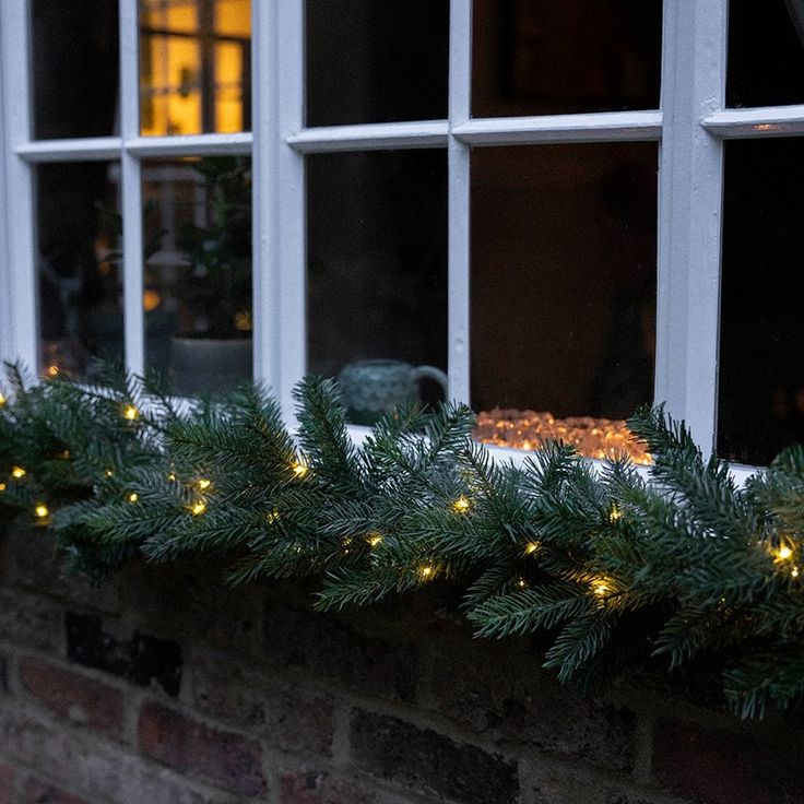 a window sill filled with christmas lights next to a brick wall