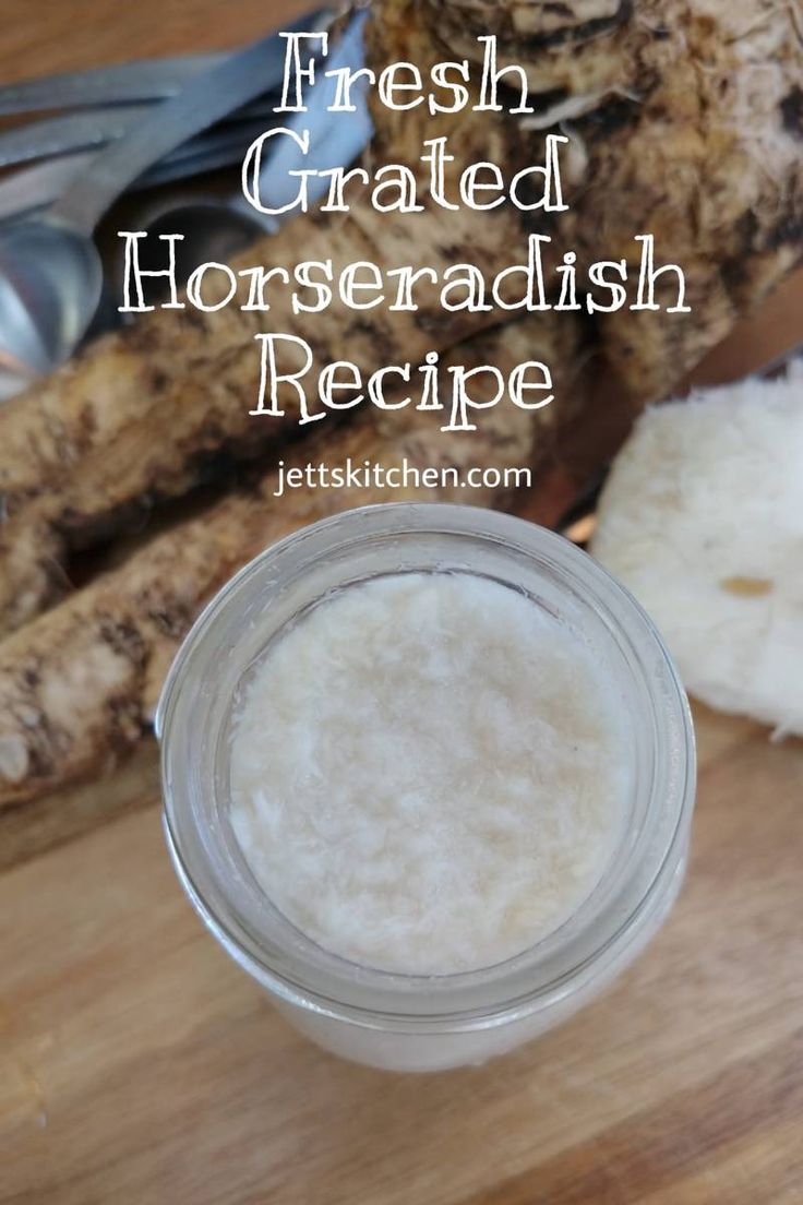 a jar filled with horseradish sitting on top of a wooden table next to sliced ginger