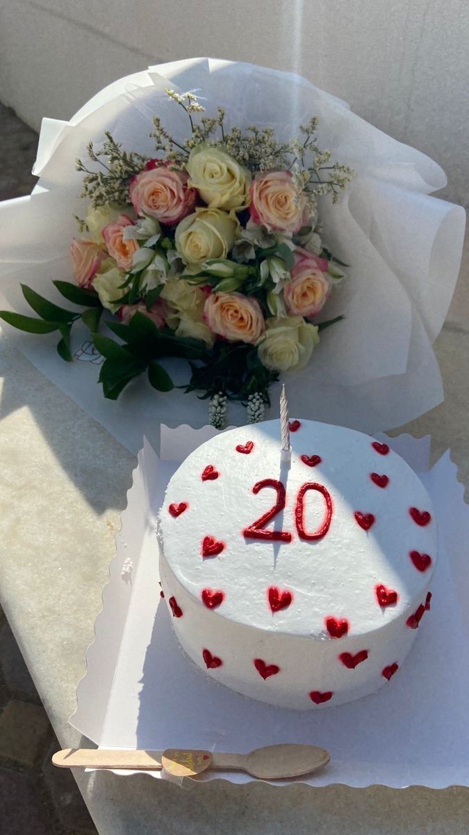 a white cake sitting on top of a table next to a bouquet of roses and a knife