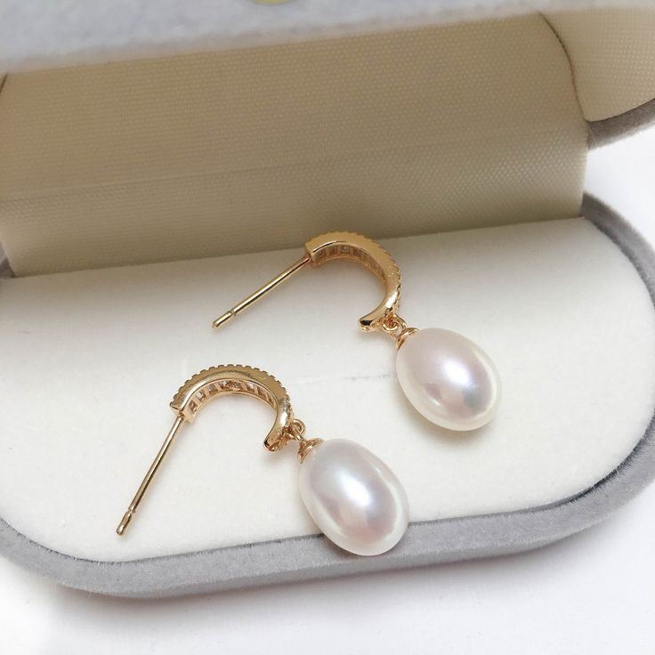 Featuring captivating oval pearls set within a graceful arch of shimmering zircons. The 18K gold plating adds a touch of modernity and makes them long-lasting, non-tarnishing for years! Pearl Type: Freshwater Pearls Pearl Quality: [Shape]: Oval [Size]: 8-9mm [Blemish]: None [Luster]: High Material: Thick 18k Gold Plated Brass Note: Every pearl is unique. Items may vary from the pictures. Luxury Oval Pearl Drop Earrings, Elegant Oval Pearl Earrings, Elegant Oval Pearl Drop Earrings, Oval Pearl Earrings For Gifts, Elegant Oval Pendant Earrings For Anniversary, Elegant Oval Gold Plated Earrings, White Oval Pearl Earrings, Luxury Gold Oval Pearl Earrings, Elegant Oval Pearl Charm Earrings