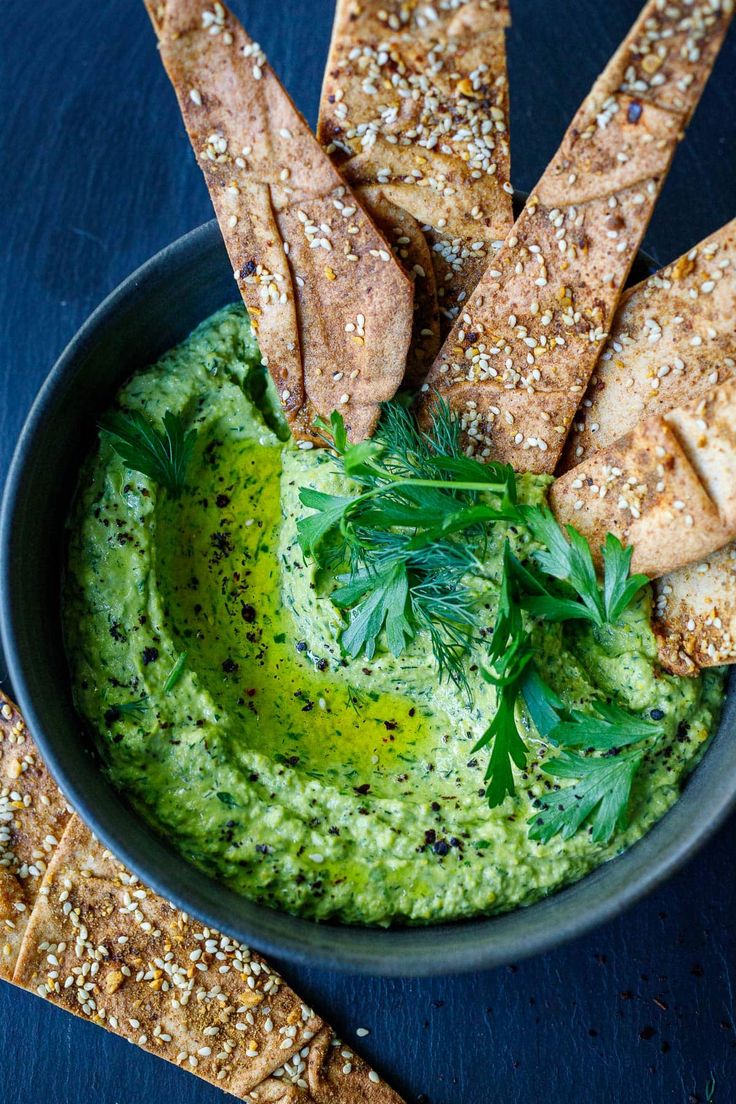 a bowl filled with hummus and pita chips on top of a blue table