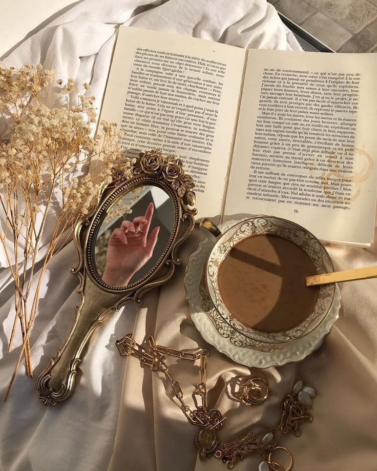 an open book with a magnifying glass on it next to a cup of coffee