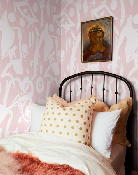 a bed with pink and white wallpaper in a small room next to a painting on the wall