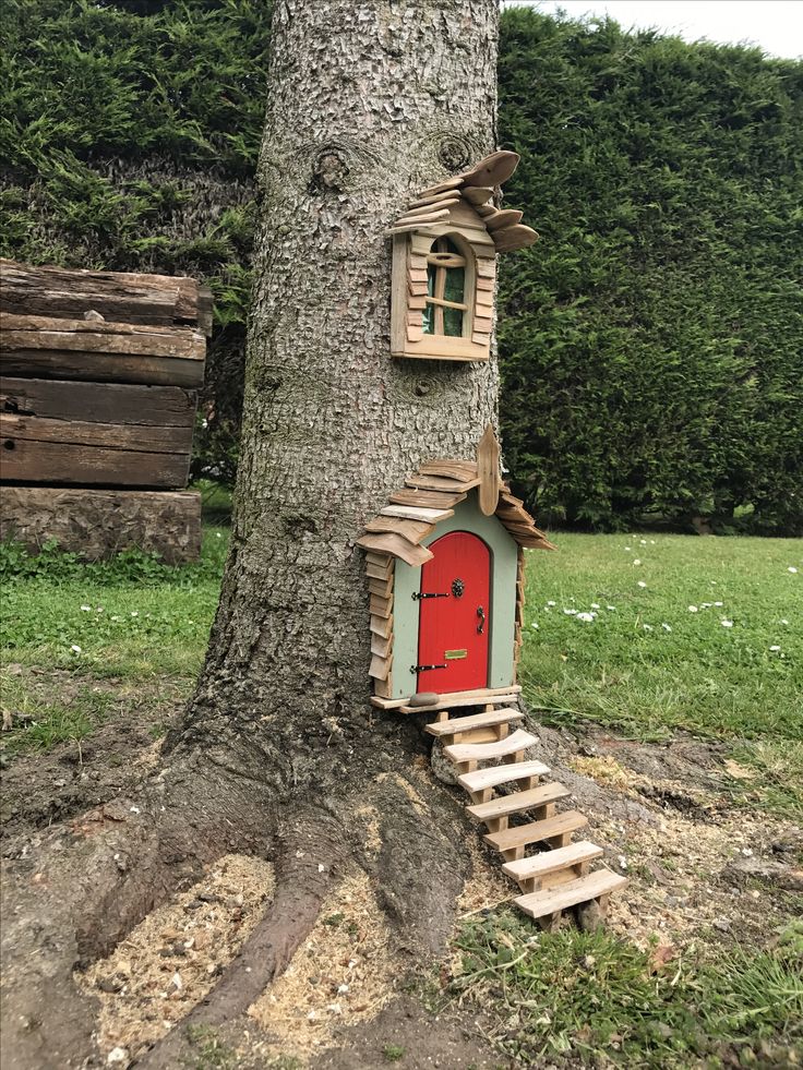 a tree with a red door and stairs made out of wood planks next to a tree trunk