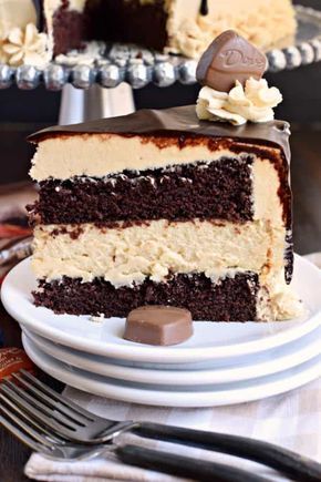 a slice of chocolate cake with white frosting on a plate next to silverware