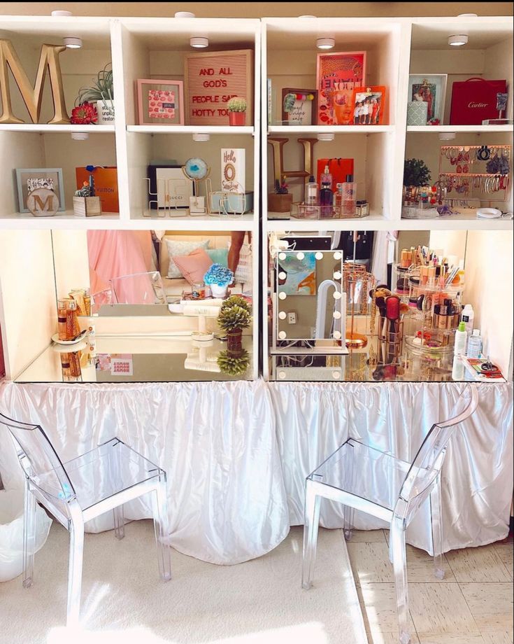 two clear chairs sitting in front of a book shelf filled with books and other items