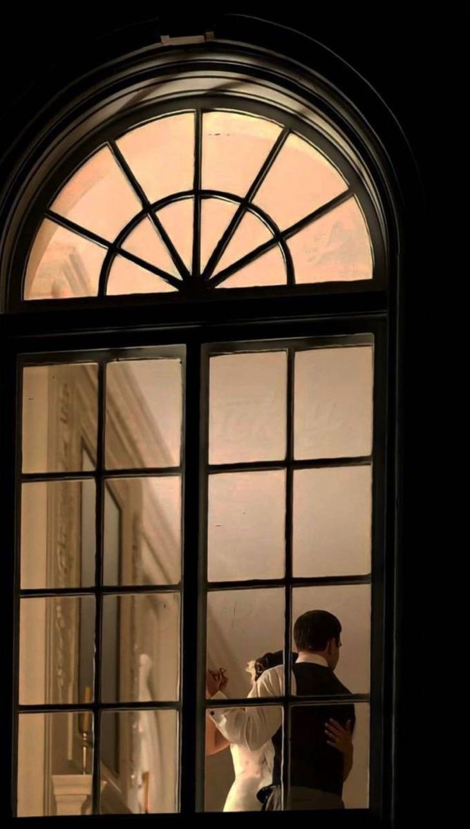 a bride and groom standing in front of a window