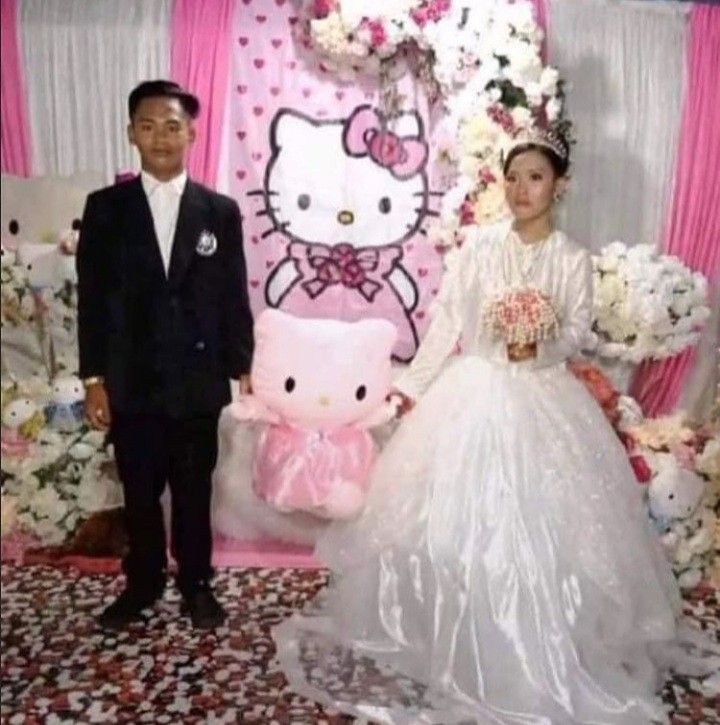 a man and woman standing in front of a hello kitty backdrop