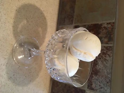 two ice creams sitting on top of a glass bowl next to a sink in a bathroom