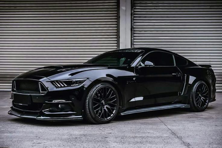 a black mustang parked in front of a garage door