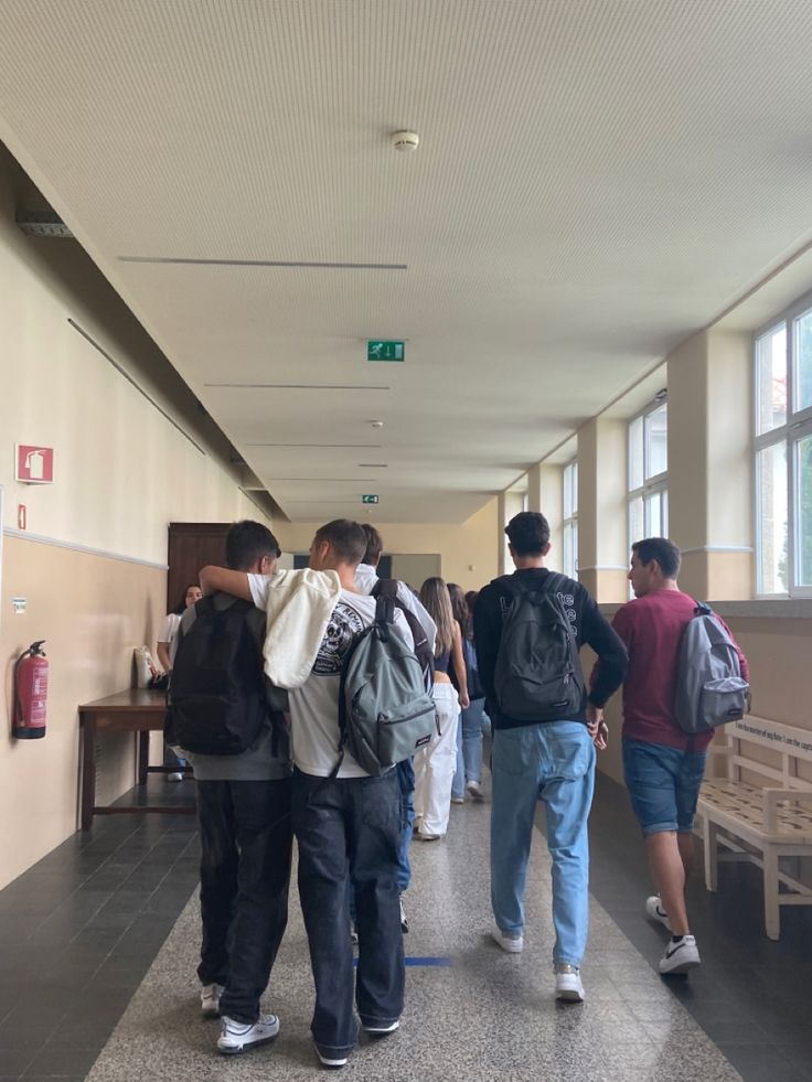 several people walking down a hallway with backpacks