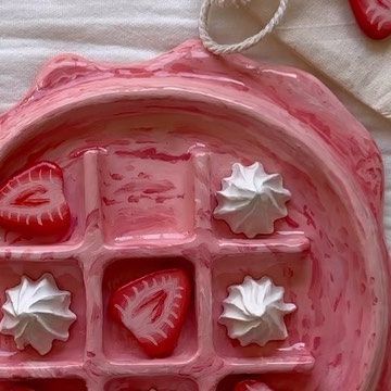 a pink bowl filled with strawberries on top of a table