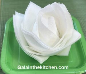 a green plate topped with white napkins on top of a table