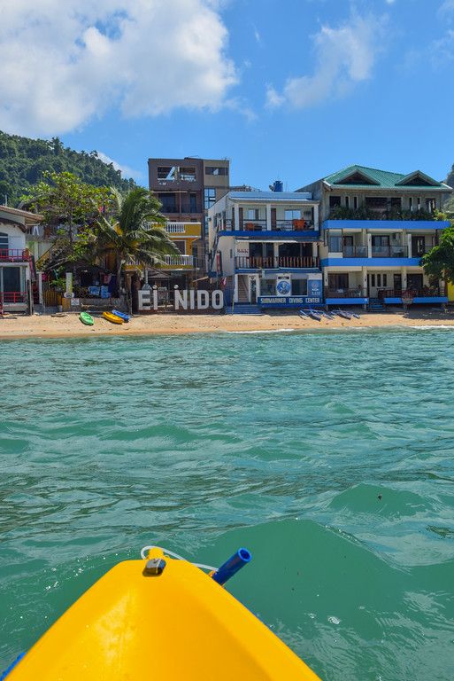 a yellow kayak is in the water next to a beach with buildings on it