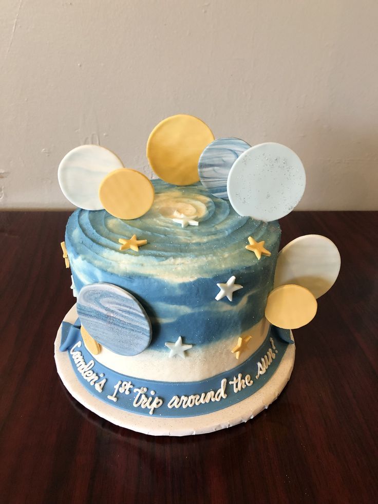 a birthday cake with stars and moon decorations on it's top, sitting on a wooden table