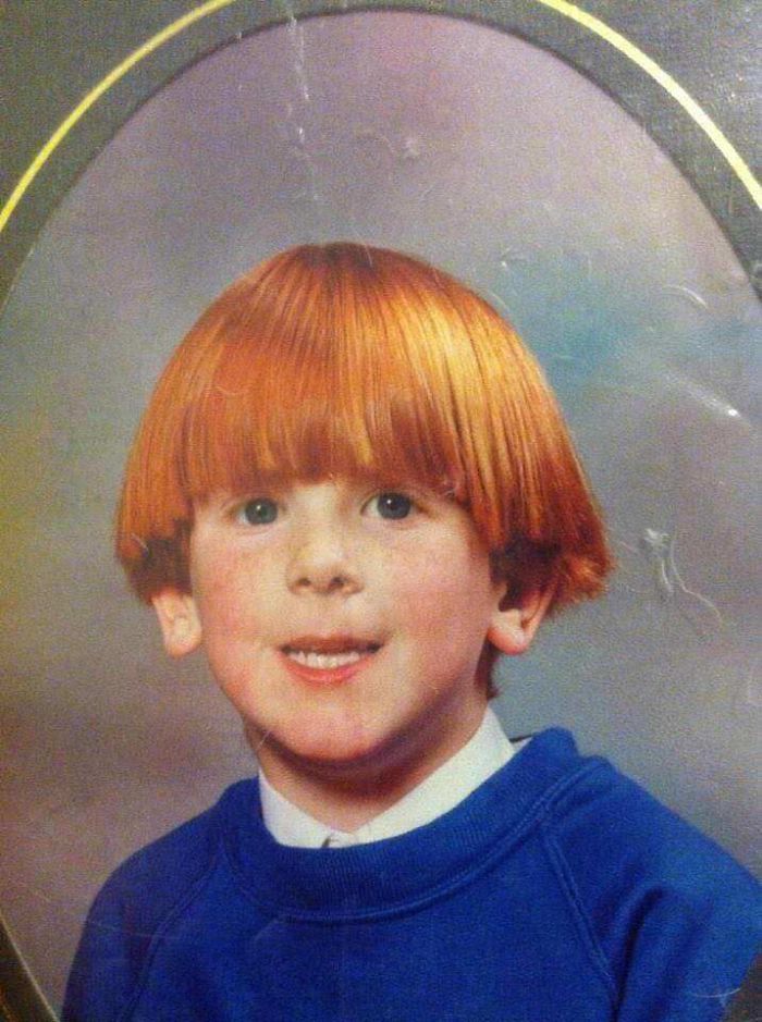 a young boy with red hair wearing a blue shirt and posing for a photo in an oval frame