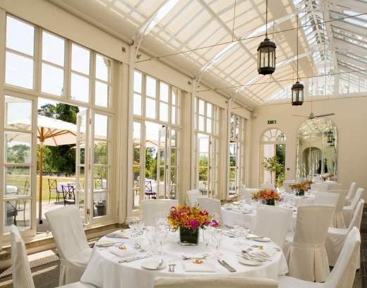 an indoor dining area with white chairs and tables set up for a formal function in front of large windows