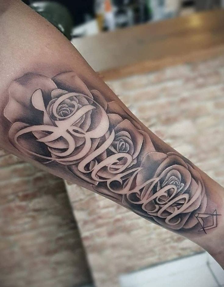 a man's arm with roses and the word love written in cursive writing