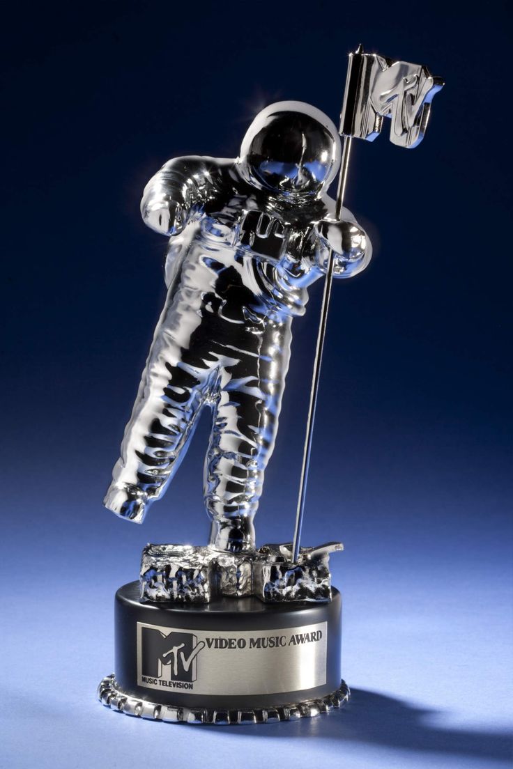 an astronaut figurine holding a flag on top of a metal base with a blue background