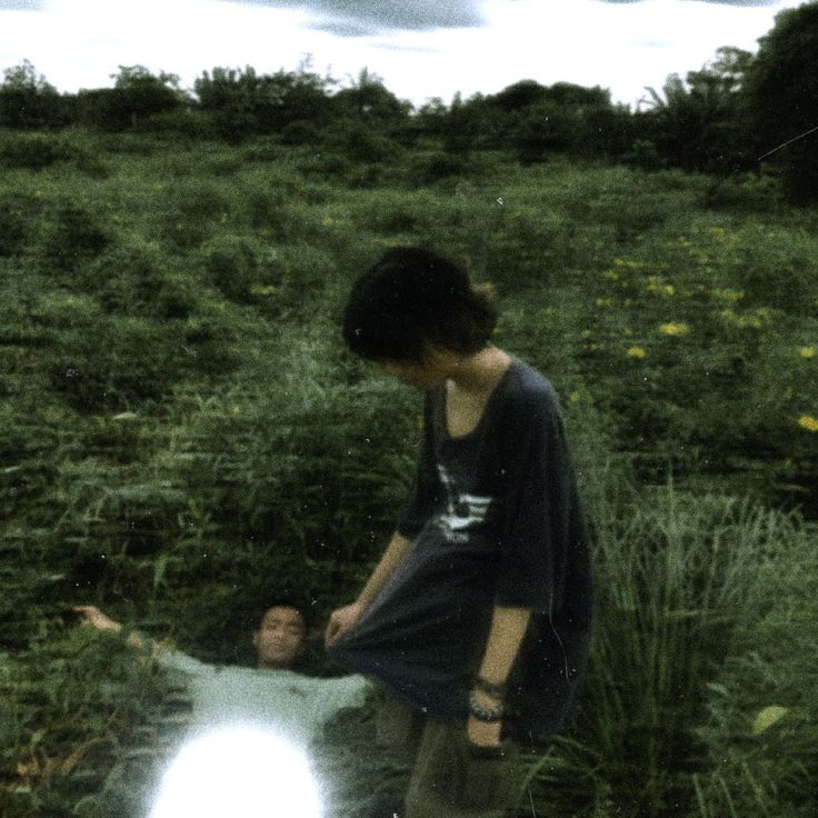 a young man standing next to a woman on top of a lush green field