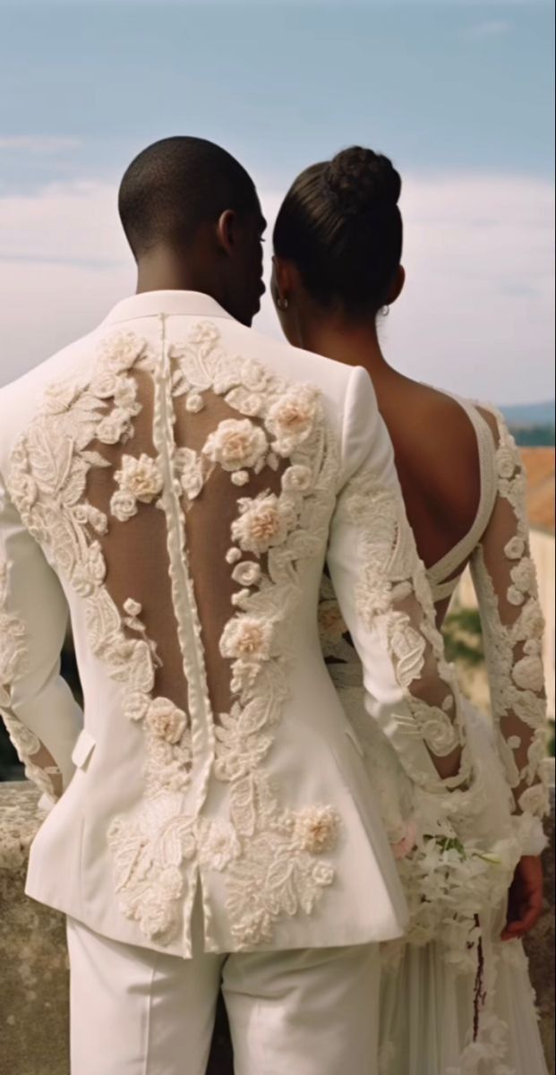 a man and woman in wedding attire standing next to each other looking at the ocean