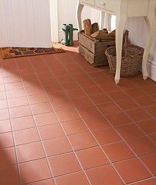 a white table sitting on top of a red tile floor next to a wooden bench