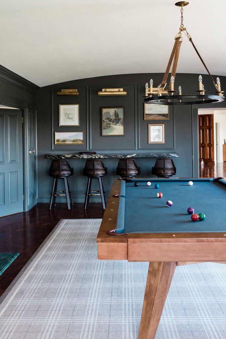 a pool table in the middle of a room with stools and pictures on the wall