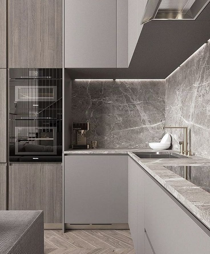 a modern kitchen with marble counter tops and grey cupboards, along with an oven