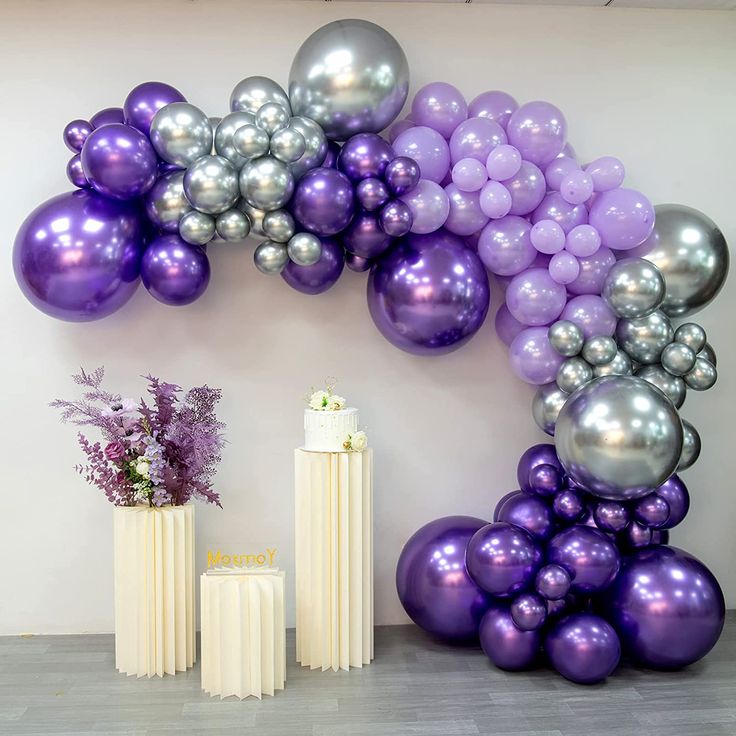 purple and silver balloons are arranged on the wall