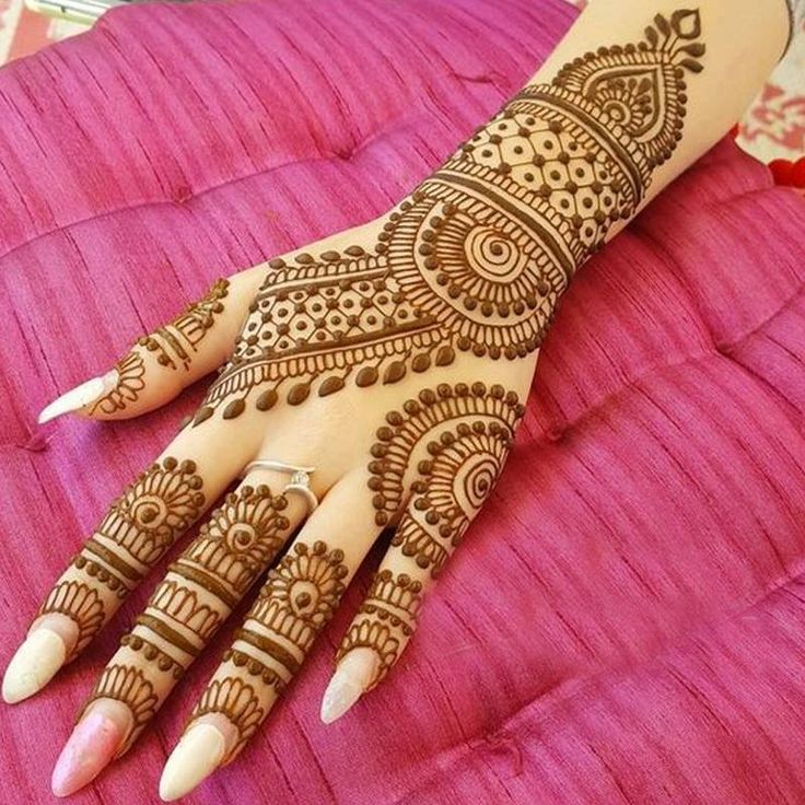 a henna on someone's hand that is sitting on a pink blanket