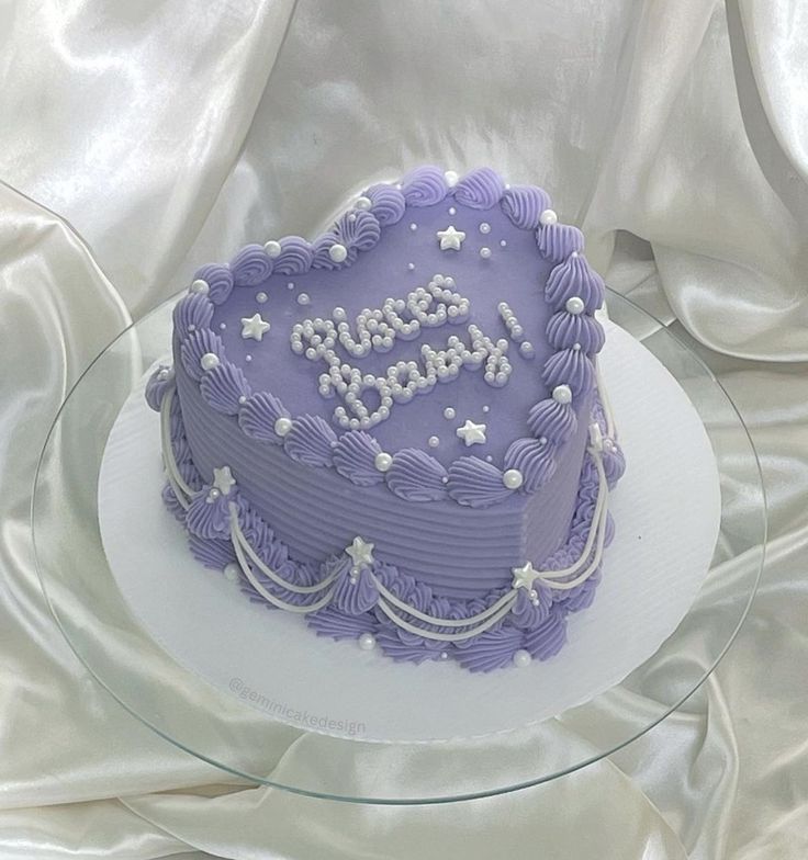 a purple birthday cake sitting on top of a glass plate