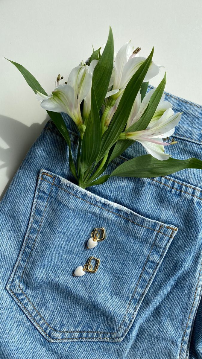 a white flower sticking out of the back pocket of a pair of blue jean shorts