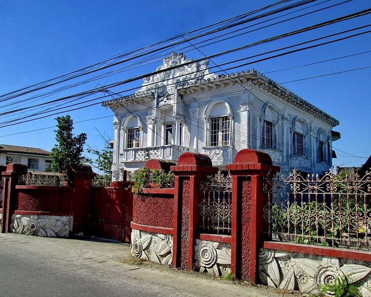 an old white house with red iron fence